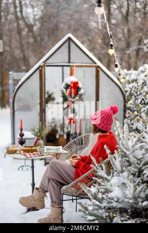 Eine Frau im verschneiten Hinterhof in den Winterferien Stockfoto