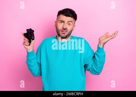 Foto von einem lustigen, grimmigen Schüler, der ein Videospiel abgestürzt hat, egal, keine Ahnung, wie das Problem gelöst werden kann Schultern zucken Gamepad isoliert auf pinkfarbenem Hintergrund Stockfoto
