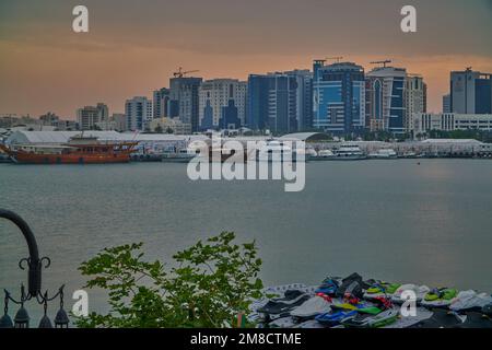 Die Skyline von Doha aus dem Box Park, ein Sonnenuntergang von Doha Katar mit Dhows im arabischen Golf und Wolken am Himmel im Hintergrund. Stockfoto