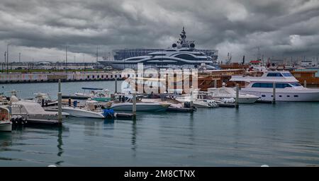 Die Skyline von Doha aus dem Box Park, ein Sonnenuntergang von Doha Katar mit Yachten und Dhows im arabischen Golf und Wolken am Himmel im Hintergrund. Stockfoto