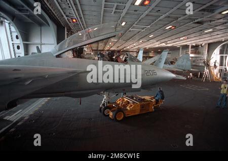 Mitarbeiter des Hangardecks verwenden einen SD-1D-Spürhund, um ein Kampfgeschwader 142 (VF-142) F-14A Tomcat aus einem Aufzug an Bord des nuklearbetriebenen Flugzeugträgers USS DWIGHT D. EISENHOWER (CVN 69) während DER FLOTTE EX '90 zu transportieren. Betreff Betrieb/Serie: FLEET EX '90 Basis: USS Dwight D Eisenhower (CVN 69) Land: Atlantik (AOC) Stockfoto