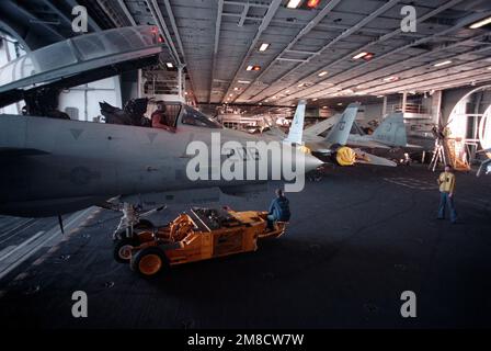 Das Personal am Hangar Deck verwendet einen SD-1D-Spürhund, um ein Kampfgeschwader 142 (VF-142) F-14A Tomcat aus einem Aufzug an Bord des nuklearbetriebenen Flugzeugträgers USS DWIGHT D. EISENHOWER (CVN-69) während DER FLOTTE EX '90 zu transportieren. Betreff Betrieb/Serie: FLOTTE EX '90 Land: Atlantik (AOC) Stockfoto