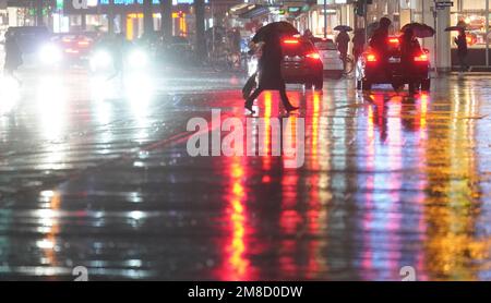 Hamburg, Deutschland. 13. Januar 2023. Passanten gehen durch eine Kreuzung im strömenden Regen. Kredit: Marcus Brandt/dpa/Alamy Live News Stockfoto