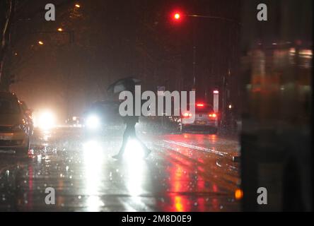 Hamburg, Deutschland. 13. Januar 2023. Ein Mann geht mit einem Schirm über die Straße. Kredit: Marcus Brandt/dpa/Alamy Live News Stockfoto