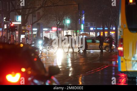 Hamburg, Deutschland. 13. Januar 2023. Passanten gehen durch eine Kreuzung im strömenden Regen. Kredit: Marcus Brandt/dpa/Alamy Live News Stockfoto