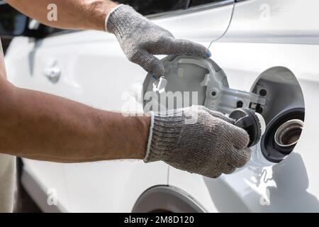 Mann öffnet die Luke des Benzintanks des Autos. Der Tanker öffnet den Gastank. Mit Handschuhen lässt sich der Gastank öffnen. Autotanken Stockfoto