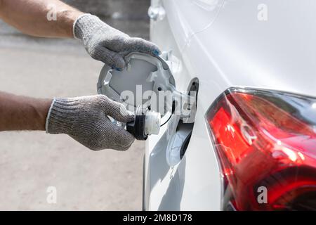 Mann öffnet die Luke des Benzintanks des Autos. Der Tanker öffnet den Gastank. Mit Handschuhen lässt sich der Gastank öffnen Stockfoto