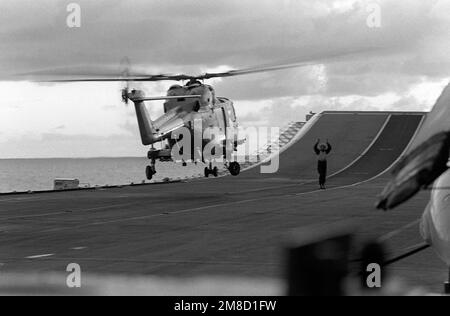 Ein Besatzungsmitglied an Bord des Leichtflugzeugträgers HMS UNBESIEGBAR (R-05) signalisiert dem Piloten eines schwebenden FLUGZEUGS. Mark 2 Lynx Helikopter während Flotte Ex 1-90. Gegenstand Betrieb/Serie: FLOTTE EX 1-90 Land: Karibik Stockfoto