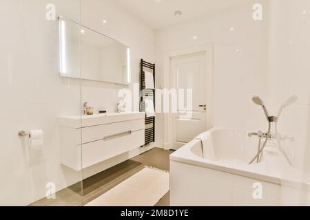 Modernes Bad mit weißen Wänden und Holzfußboden sowie freistehender Badewanne in der Ecke Stockfoto