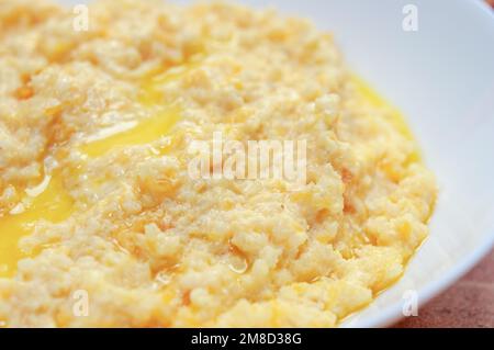 Nahaufnahme von Kürbisbrei mit Hirse, serviert in einer weißen Schüssel, selektiver Fokus, horizontaler Schuss. Stockfoto