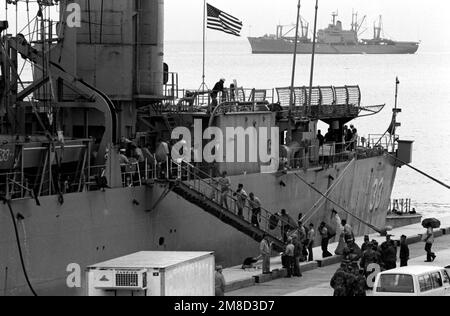 Eine Arbeitsgruppe transportiert Taschen mit Post auf das Dock-Landungsschiff USS ALAMO (LSD-33), während das Schiff im Hafen ist, um Ausrüstung und Vorräte vor dem kombinierten südkoreanischen/US-Übungsteam Spirit '90 zu übernehmen. Das Amphibienschiff USS ST. LOUIS (LKA-116) ist im Hintergrund. Betreff Operation/Serie: TEAMGEIST '90 Staat: Okinawa Land: Japan (JPN) Stockfoto