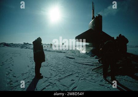 Besatzungsmitglieder kommen aus dem nuklearbetriebenen Angriffs-U-Boot USS SEAHORSE (SSN 669) kurz nachdem das Schiff während der Übung ICE EX '90 durch das Eis am Nordpol aufgetaucht war. Das Segel des nuklearbetriebenen Angriffs-U-Boots USS GURNARD (SSN 662), das ebenfalls gerade aufgetaucht ist, ist am Horizont zu sehen. Betrifft Operation/Serie: ICE EX '90 Land: Nordsee Stockfoto