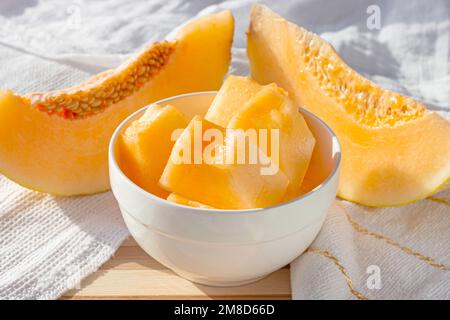 Frische süße, saftige Honigmelone (Cantaloupe) in Scheiben in einer weißen Schüssel in der Küche im Sommer. Stockfoto