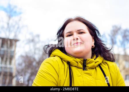 Glücklich attraktiv mollig übergewichtig kaukasische Frau lächelnd Porträt im Freien. Fröhliche hübsche Körper positive Person lachend während des Spaziergangs im Park. Stockfoto