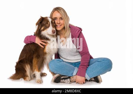 Junge Frau mit australischem Hirtenhund auf weißem Hintergrund Stockfoto