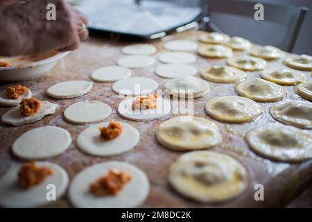 Füllung und Versiegelung von Blätterteigknödeln in einer Küche. Lifestyle Stockfoto