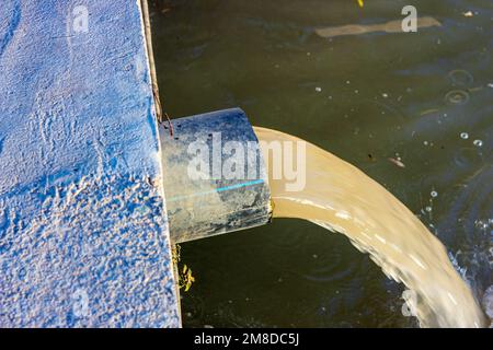 Die Abwasserabwasserleitung pumpt das verschmutzte Wasser in den Fluss. Wasserverschmutzung, Umweltkontaminationskonzept. Stockfoto