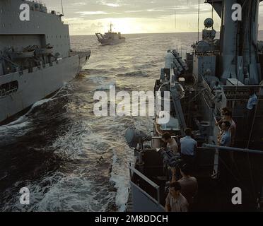 Der geführte Raketenkreuzer USS JOSEPHUS DANIELS (CG-27), rechts, kommt zusammen mit einem Flottenöler des militärischen Sealift-Kommandos, um während der Unitas XXXI, einer kombinierten Übung, an der die Marinekräfte der Vereinigten Staaten und neun südamerikanische Nationen beteiligt sind, eine laufende Auffüllung durchzuführen. Das Panzerlandeschiff USS HARLAN COUNTY (LST-1196) befindet sich im Hintergrund. Betreff Betrieb/Serie: UNITAS XXXI Land: Unbekannt Stockfoto