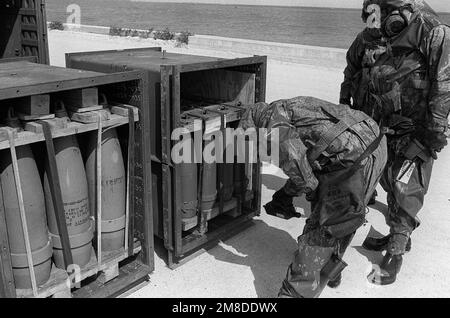 Zwei Soldaten in voller Schutzausrüstung sehen zu, wie ein dritter Soldat einen Chemieüberwacher benutzt, um offene Behälter mit chemischer Munition auf undichte Kugeln zu überprüfen. Mitglieder des 71. Chemical Regiment, 25. Infantry Division (Light), nehmen an einer Übung Teil, die die Fähigkeit der Einheit testen soll, ein Chemikalienleck zu erkennen und zu mindern. Basis: US Army Chemical Activity Country: Johnston Atoll Stockfoto