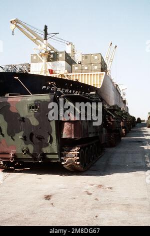 Amphibienfahrzeuge der Marine AAVP-7A1 säumen den Pier neben dem Seeschiff PFC. Dewayne T. Williams (T-AK-3009) während der Operation Desert Shield. Betreff Operation/Serie: WÜSTENSCHILD Land: Saudi-Arabien (Sau) Stockfoto