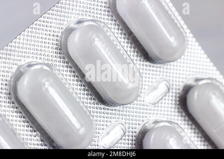 Silberne und weiße Folienblisterpackung mit medizinischen Pillen auf hellem Hintergrund Nahaufnahme. Stockfoto