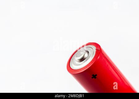 Leuchtend rote Alkaline-Batterie aus Metall, mit Pluszeichen auf hellem Hintergrund, Nahaufnahme mit Kopierbereich. Stockfoto