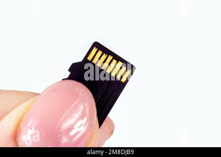 Kaputte Micro-sd-Speicherkarte mit rostigen Kontakten auf dem Chip in den Händen der Frau. Stockfoto