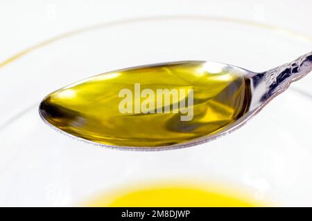 Gelbes Bio-Olivenöl im Löffel auf hellem Hintergrund Nahaufnahme. Stockfoto