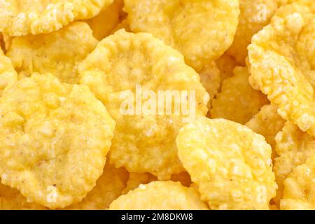 Leuchtend gelbe leckere zuckerknusprige Cornflakes zum Frühstück als Nahaufnahme der Textur. Stockfoto