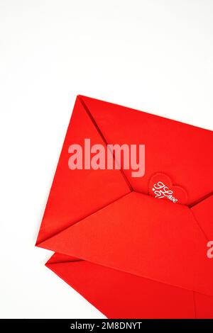 Valentinskarte mit Umschlag und kleinen Herzen auf rotem Papierhintergrund, Draufsicht, Kopierbereich Stockfoto