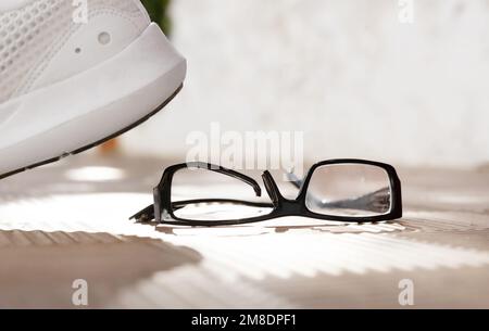 Fuß trat auf eine Brille. Unfall auf St. Zerbrochene Gläser auf Straßenfliesen Stockfoto