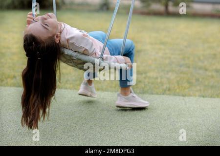 Portrait von fröhlichen Mädchen schwingt auf Korbschaukel für Spaziergang im Freien an sonnigen Sommertag. Freudige Emotionen. Freude an der Kindheit. . Hochwertige Fotos Stockfoto