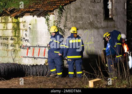 Erkelenz, Deutschland. 13. Januar 2023. Am dritten Tag der Evakuierung des von Klimaktivisten besetzten Braunkohlendorfes Lützerath kommen die Einsatzkräfte des Deutschen Bundesamtes für Technische Hilfe (THW) aus einem Gebäude mit Leiter. Hier sollen sich Aktivisten in einem Tunnel verbarrikadiert haben. Das Energieunternehmen RWE will die unter Lützerath liegende Kohle ausheben - zu diesem Zweck soll das Weiler auf dem Gebiet der Stadt Erkelenz am Braunkohlebergwerk Garzweiler II abgerissen werden. Kredit: Thomas Banneyer/dpa/Alamy Live News Kredit: dpa Picture Alliance/Alam Stockfoto