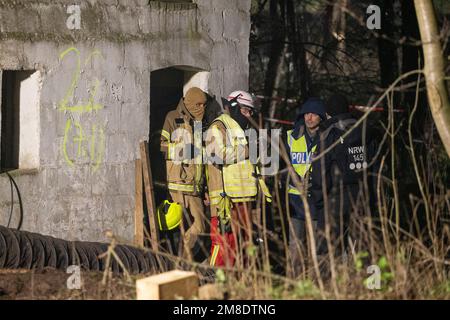 Erkelenz, Deutschland. 13. Januar 2023. Polizeibeamte und Feuerwehrleute stehen am dritten Tag der Evakuierung des Braunkohlendorfes Lützerath, das von Klimaschutzaktivisten besetzt war, vor dem Eingang zu einem Gebäude. Hier sollen sich Aktivisten in einem Tunnel verbarrikadiert haben. Das Energieunternehmen RWE will die unter Lützerath liegende Kohle ausheben - zu diesem Zweck soll das Weiler auf dem Gebiet der Stadt Erkelenz am Braunkohlebergwerk Garzweiler II abgerissen werden. Kredit: Thomas Banneyer/dpa/Alamy Live News Kredit: dpa Picture Alliance/Alamy Live News Stockfoto