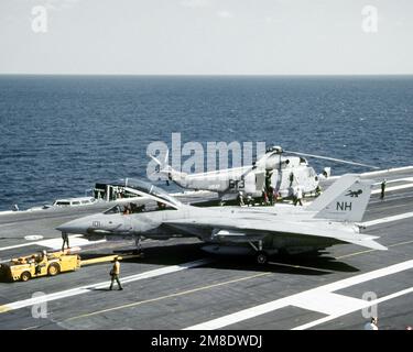 Ein Schlepper MD-3A wird verwendet, um ein Flugzeug des Kampfgeschwaders 114 (VF-114) F-14A Tomcat auf dem Cockpit des nuklearbetriebenen Flugzeugträgers USS ABRAHAM LINCOLN (CVN-72) zu transportieren. Im Hintergrund befindet sich ein Hubschrauber zur U-Boot-Abwehr-Staffel 17 (HS-17) SH-3H Sea King. Land: Atlantik (AOC) Stockfoto