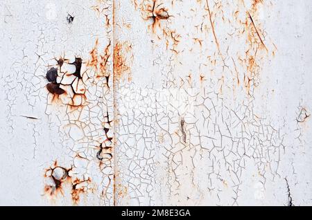 Strukturierte graue Oberfläche mit gerissener alter Farbe und rostigem Metall als abstrakter Hintergrund. Stockfoto