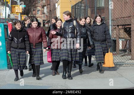 Orthodoxe jüdische Schulmädchen, die die gleichen Uniformen tragen, laufen auf der Bedford Avenue in Williamsburg nach dem Unterricht. Stockfoto