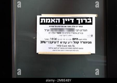 Ein jiddisches und hebräisches Schild vor einer Synagoge, das den Tod eines Gläubigen ankündigt. Es beinhaltet einen Segen für Gott. In New York City Stockfoto