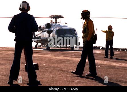 Besatzungsmitglieder an Bord des Amphibienschiffs USS NASSAU (LHA-4) halten sich bereit, während ein Marine Helicopter Squadron 1 (HMX-1) VH-60D Black Hawk (Blackhawk) mit Präsident George Bush und seiner Gruppe an Bord eintrifft. Der Präsident besucht an Thanksgiving US-Militärangehörige, die für Operation Desert Shield in der Region des Persischen Golfs eingesetzt werden. Betroffene Operation/Serie: WÜSTENSCHILD Land: Unbekannt Stockfoto