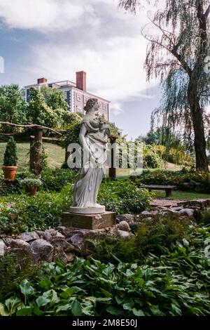 Eine weiße Statue einer Göttin steht in einem italienischen Garten mit dem Haus im Hintergrund auf dem Codman Estate. Lincoln, Massachusetts. Das Bild war ca. Stockfoto