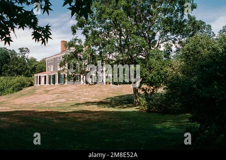 Das Haupthaus auf dem Hügel hinter Bäumen im Codman Estate. Lincoln, Massachusetts. Das Bild wurde auf analogem Film aufgenommen. Stockfoto