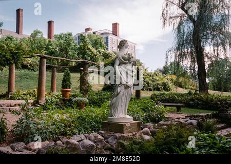 Eine weiße Statue einer Göttin steht in einem italienischen Garten mit dem Haus im Hintergrund auf dem Codman Estate. Lincoln, Massachusetts. Das Bild war ca. Stockfoto