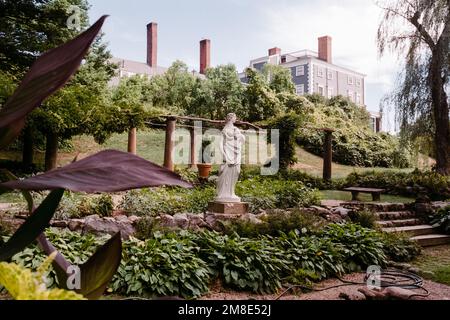 Eine weiße Statue einer Göttin steht in einem italienischen Garten mit dem Haus im Hintergrund auf dem Codman Estate. Lincoln, Massachusetts. Das Bild war ca. Stockfoto