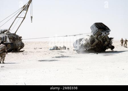 Ein Marine sieht zu, wie ein gepanzertes Bergungsfahrzeug M-88A1 einen umgestürzten M-60-Hauptpanzer aufragt. Die Übung, Teil der Operation Desert Shield, simuliert eine mögliche Situation auf dem Schlachtfeld. Betreff Operation/Serie: WÜSTENSCHILD Land: Saudi-Arabien (Sau) Stockfoto