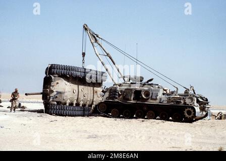 Ein Marine sieht zu, wie ein gepanzertes Bergungsfahrzeug M-88A1 einen umgestürzten M-60-Hauptpanzer aufragt. Die Übung, Teil der Operation Desert Shield, simuliert eine mögliche Situation auf dem Schlachtfeld. Betreff Operation/Serie: WÜSTENSCHILD Land: Saudi-Arabien (Sau) Stockfoto