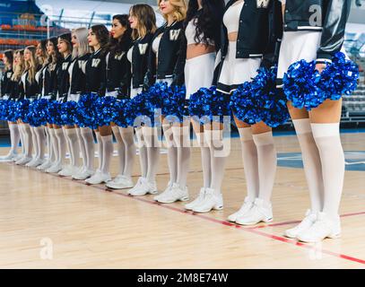 Cheerleader in Miniröcken und kniehohen Socken, die Pom-Poms halten, konzentrieren sich auf ihre Beine. Stockfoto