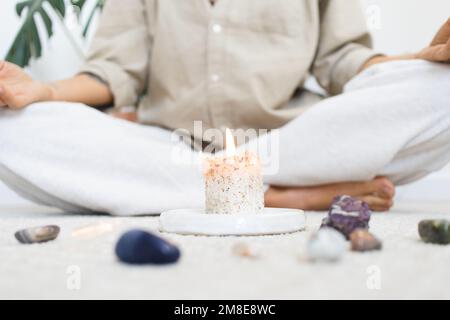 Person, die mit Kerzen und Kristallen meditiert Stockfoto