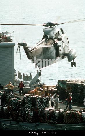 Ein SH-3H Sea King Hubschrauber schwebt über dem Flugdeck des Kampfladenschiffs USS NIAGARA FALLS (AFS-3), während während während der Operation Desert Storm mehrere Bündel an Bord gehoben werden. Betreff Operation/Serie: WÜSTENSTURMBASIS: USS New Jersey (BB 62) Stockfoto