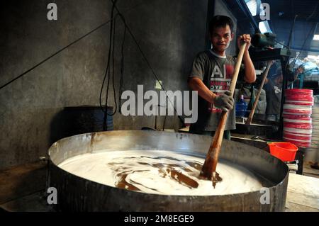 Depok, WEST JAVA, Indonesien. 12. Januar 2023. Arbeiter bereiten „Kue Keranjang“ (Korbkuchen) in einem traditionellen Kuchenmacher zu, der seit 35 Jahren in Depok, West Java, Indonesien, am 13. Januar 2023 in Betrieb ist. Klebriger Reis und Zucker und hat eine kaute und klebrige Konsistenz, die 15 Stunden gekocht wird. Vor den chinesischen Neujahrsfeiern stiegen die Verkäufe dieser Kuchen, insbesondere in der chinesischen Gemeinde in Indonesien. (Kreditbild: © Dasril Roszandi/ZUMA Press Wire) NUR REDAKTIONELLE VERWENDUNG! Nicht für den kommerziellen GEBRAUCH! Stockfoto