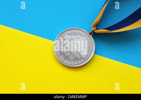 KIEW, UKRAINE - 4. MAI 2022 Medaille für die Person, die den Hoverla erobert hat. Ukrainischer Touristensouvenir-Preis auf einem Band mit den Farben der ukrainischen Flagge Stockfoto